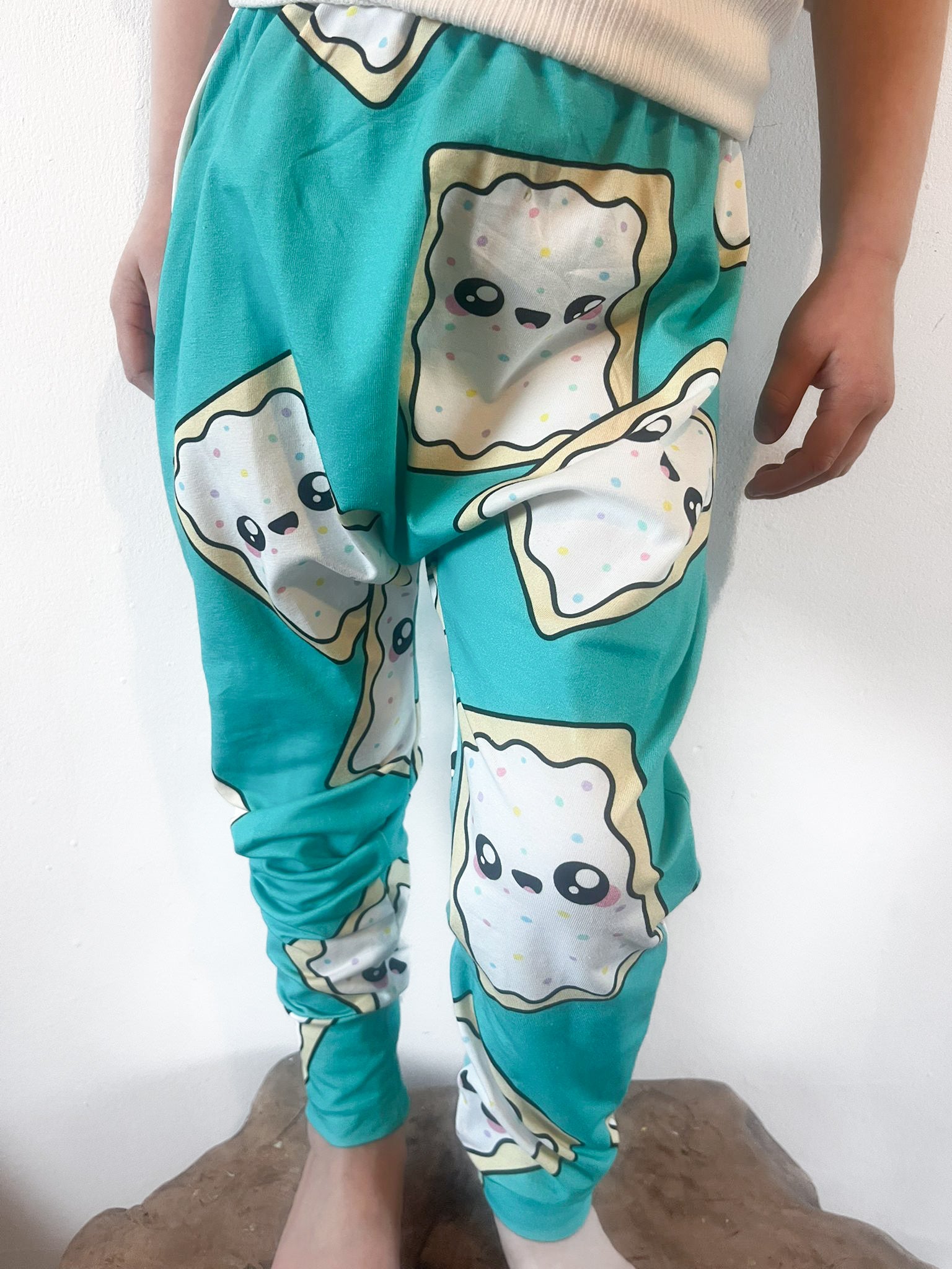 Child wearing turquoise baggy harem pants with cartoon pop-tart print and sprinkles
