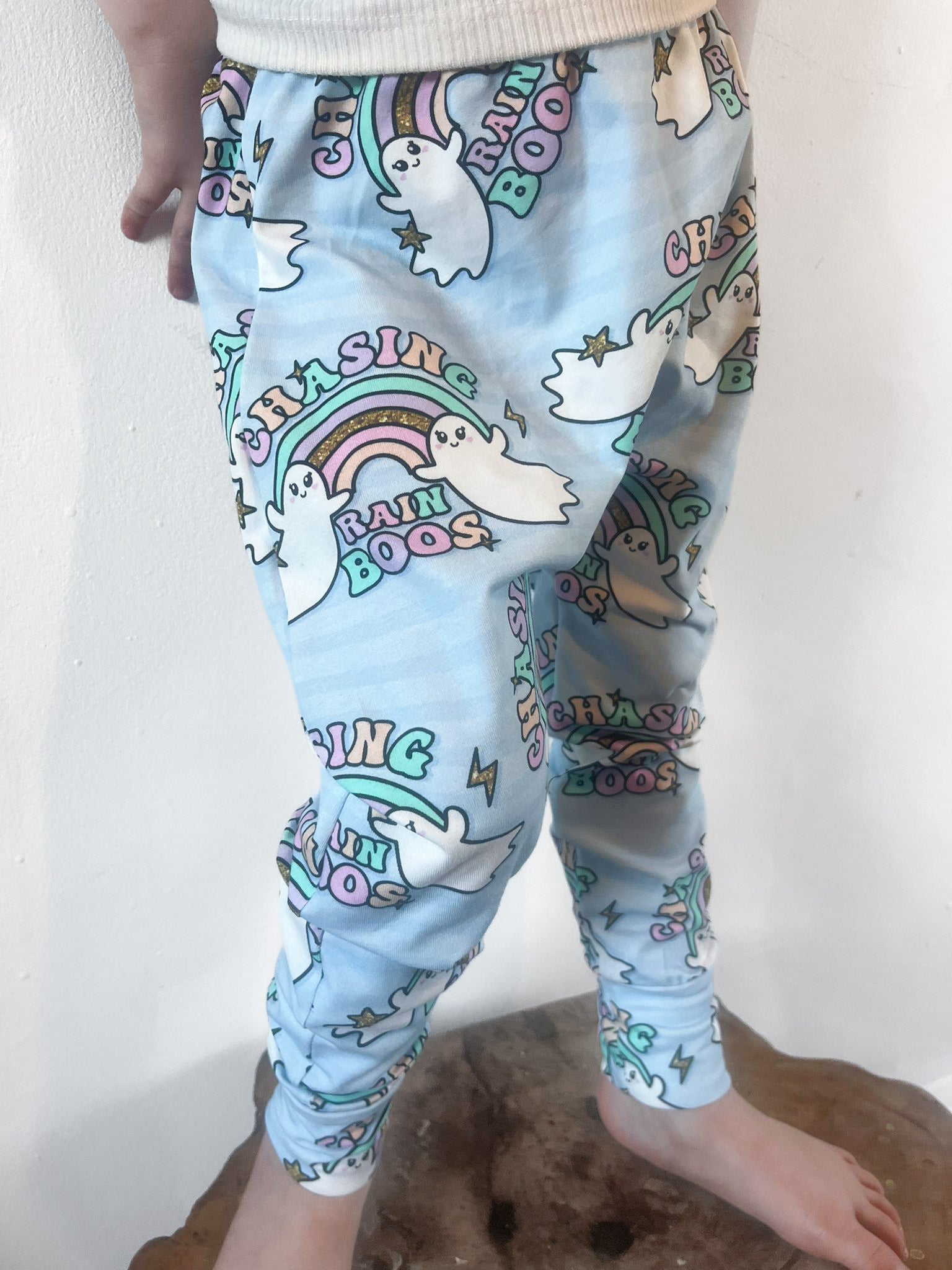 Child wearing pastel blue harem pants with ghost and rainbow print and ‘Chasing Rainboos’ text