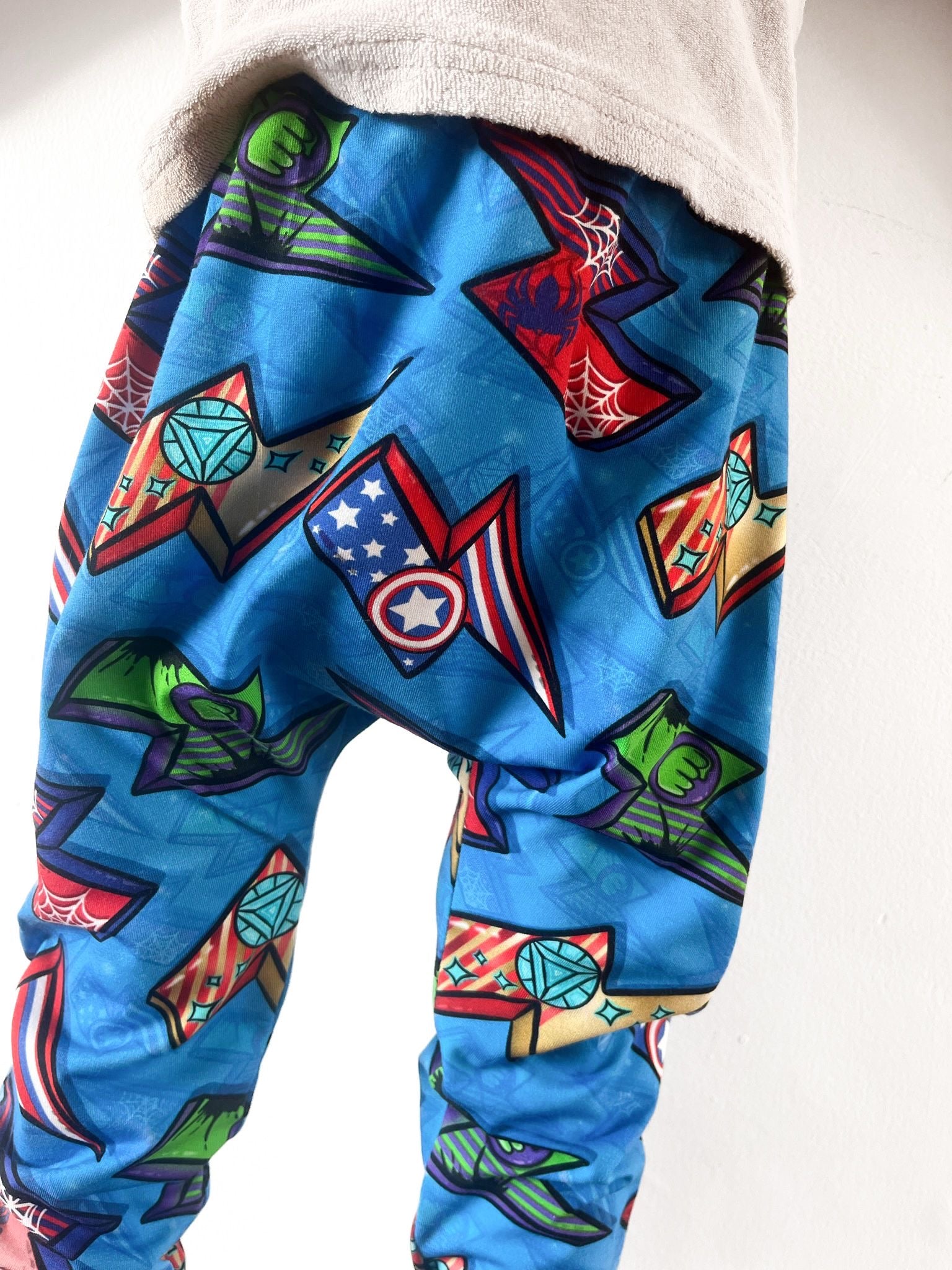 Kids harem pants with superhero comic print featuring shields, webs, and powers