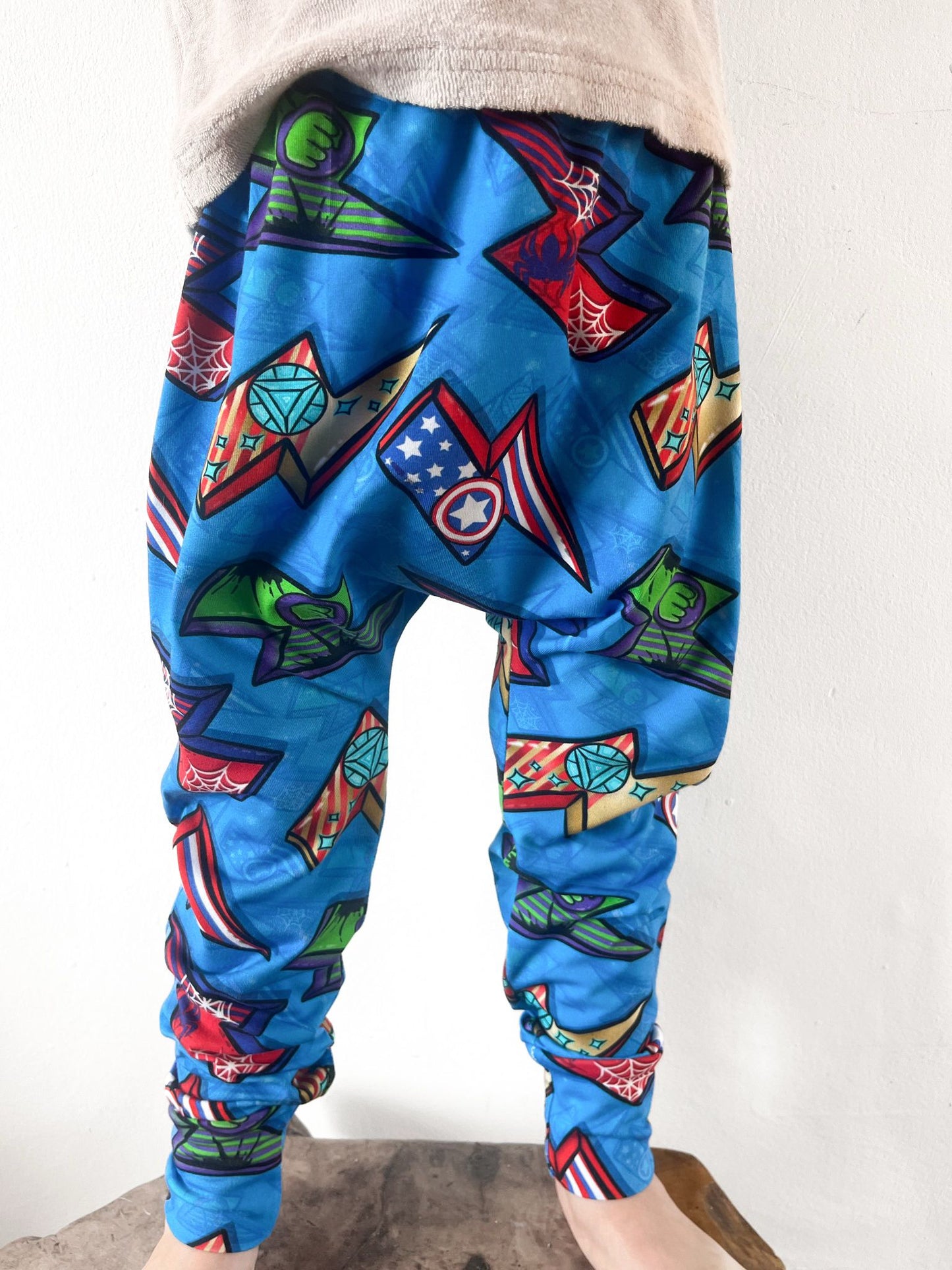 Kids harem pants with superhero comic print featuring shields, webs, and powers