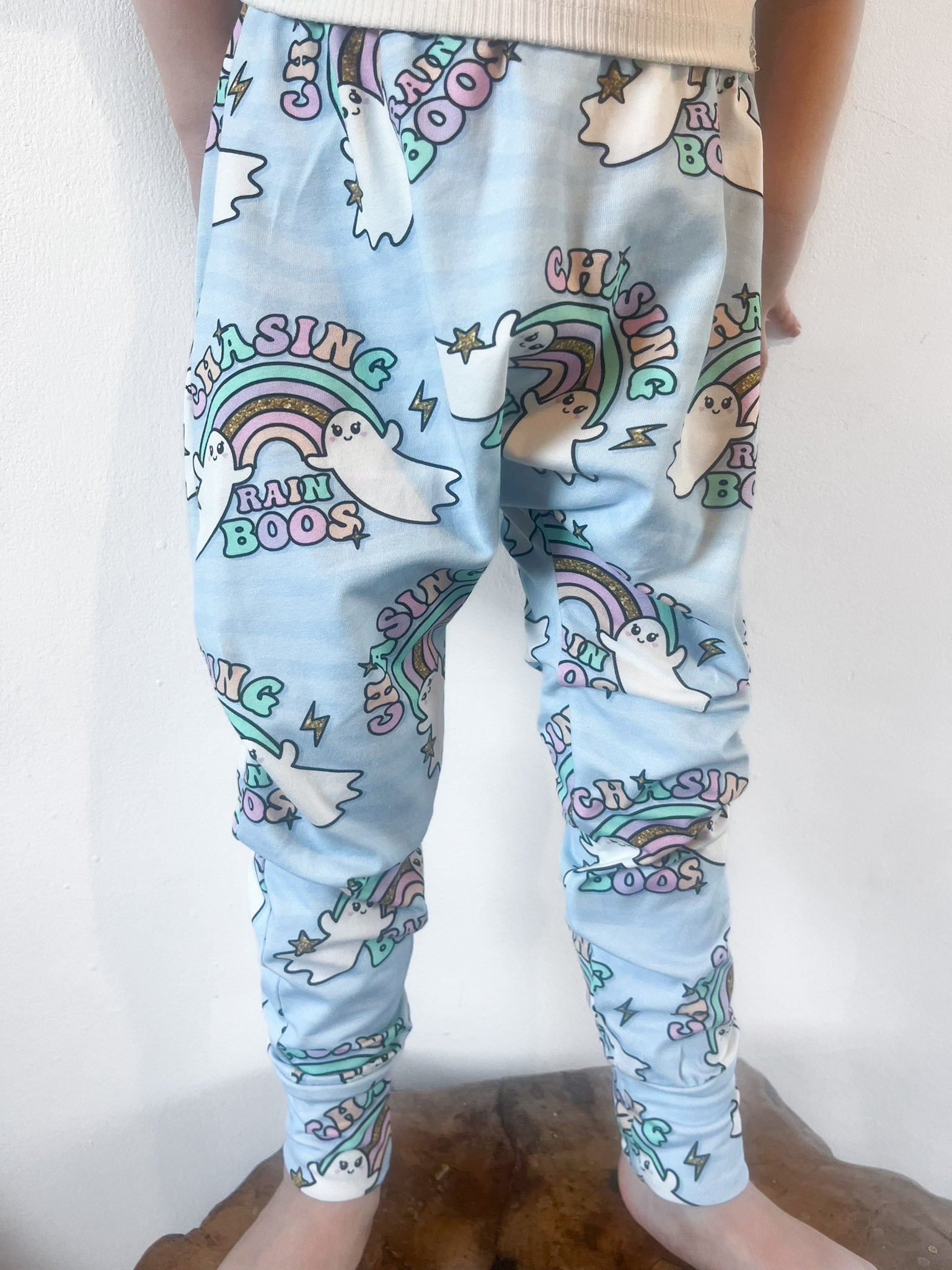 Child wearing pastel blue harem pants with ghost and rainbow print and ‘Chasing Rainboos’ text