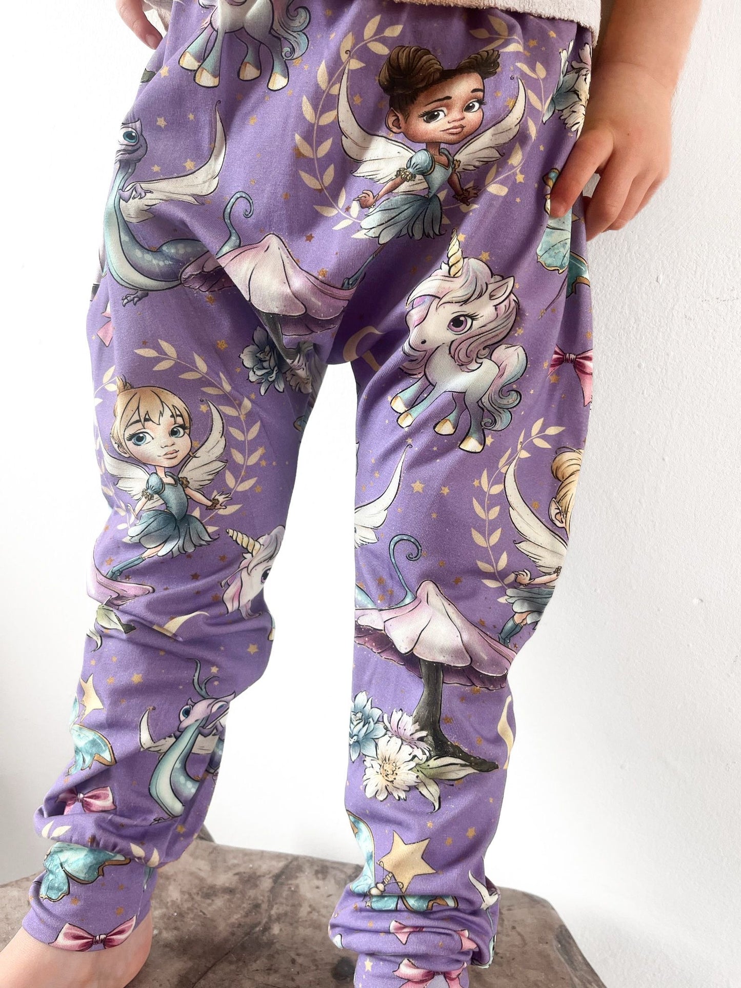 Kids harem pants with purple fairyland print including fairies, unicorns, and dragons