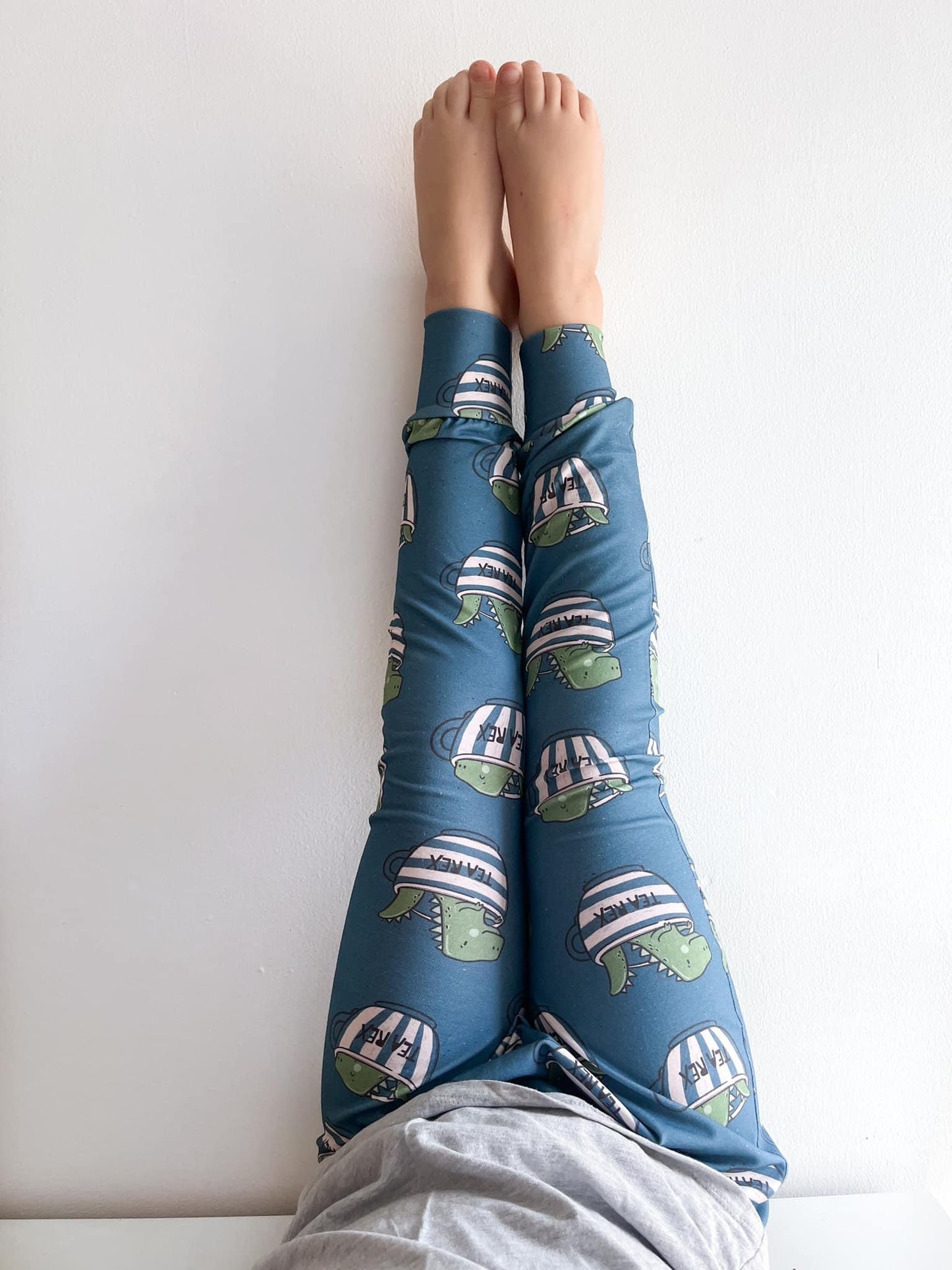 Close-up of toddler wearing dinosaur print harem pants labeled Tea Rex.