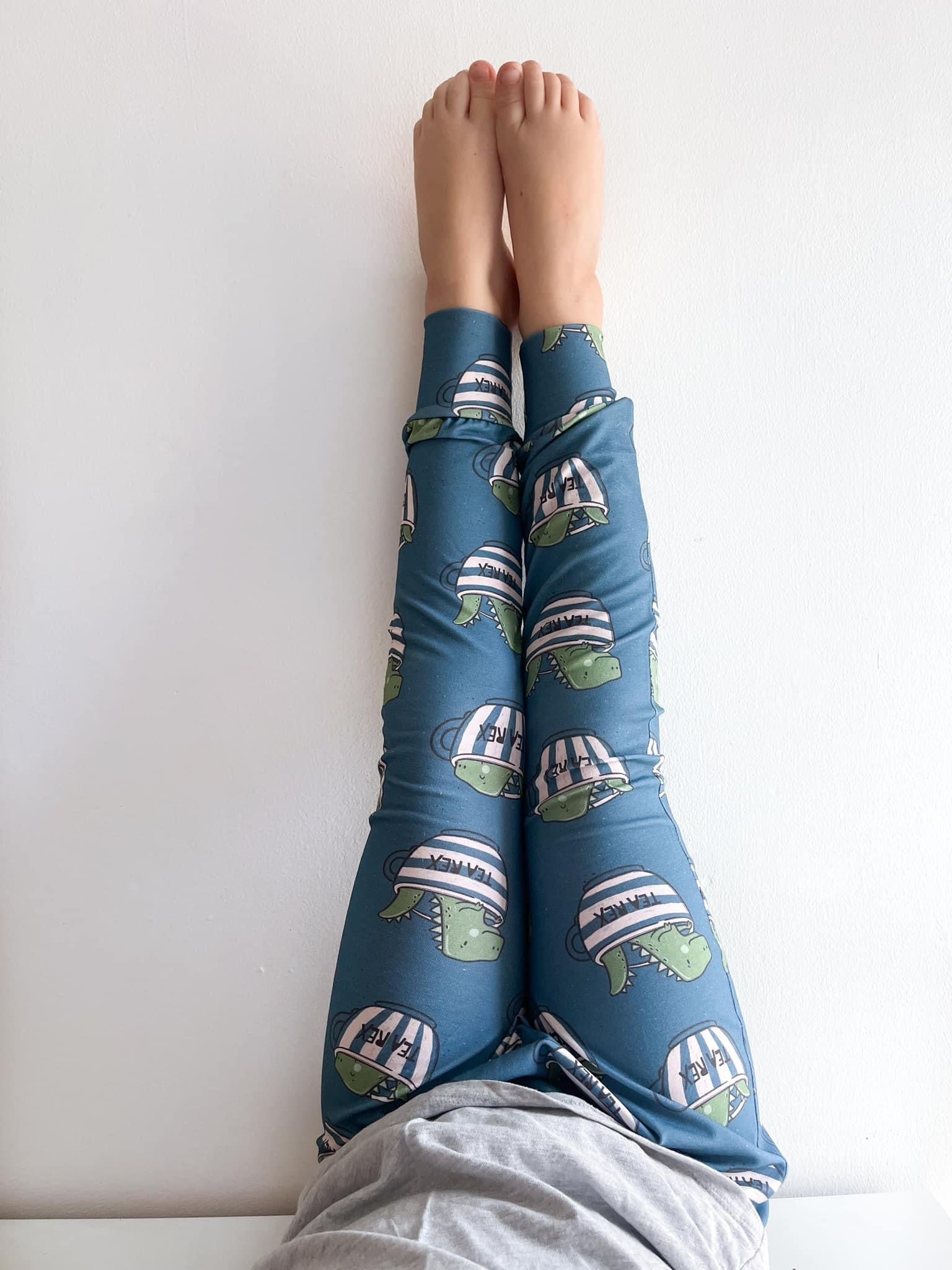 Close-up of toddler wearing dinosaur print harem pants labeled Tea Rex.